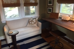 The indoor sun porch serves as a study with a draftsman table desk and a Pottery Barn couch.